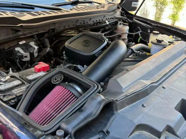 Car engine with open hood and air filter.